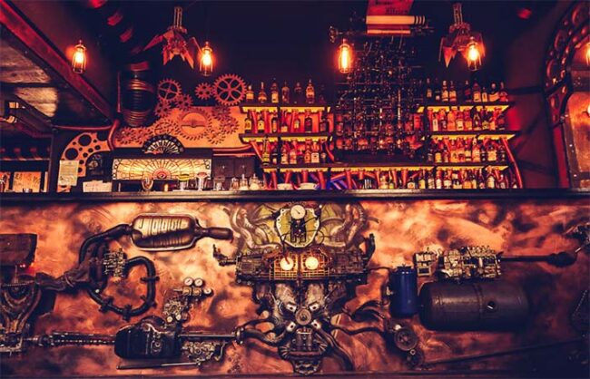 Détail des mécanismes en cuivre et engrenages décoratifs sur les murs de l'Enigma Café steampunk en Roumanie
