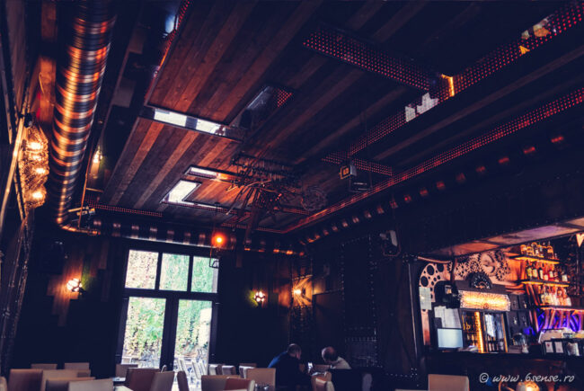 Intérieur gothique et victorien de l'Enigma Café à Cluj-Napoca avec mobilier en bois sombre et éclairage à filament