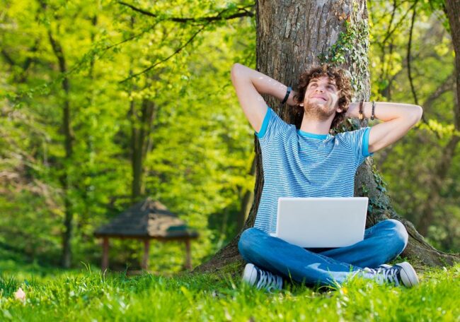 Young man in a park enjoying with laptop